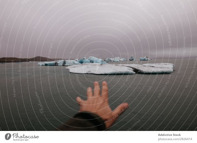 Crop hand outstretched to glacier Man Glacier Ocean Iceland Hand Outstretched Landscape Iceberg Vantage point Coast Gloomy scenery Extreme seaside Adventure