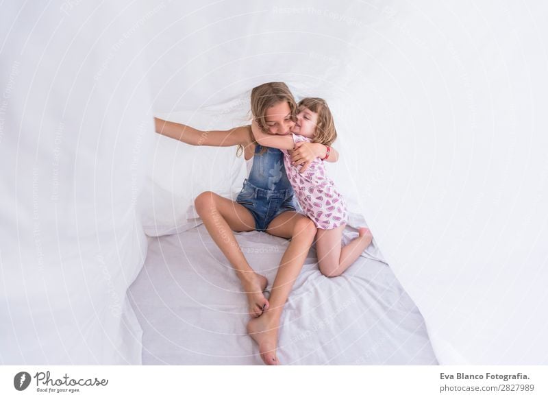 Two beautiful sister kids playing under white sheets Lifestyle Joy Happy Beautiful Leisure and hobbies Playing Reading Summer Bedroom Child Human being Feminine