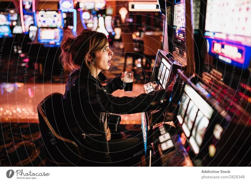 Side view of woman sitting in casino and playing slot machine. female gambling game risk luck player winner gaming gamble gambler lucky nightlife fortune