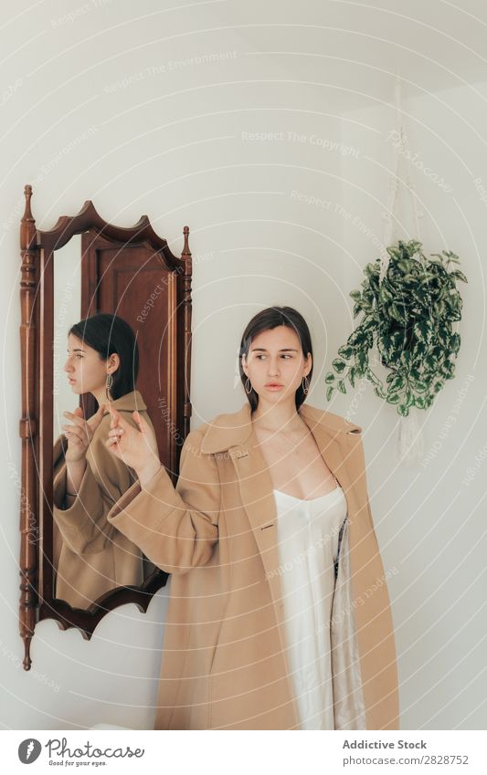 Stylish woman posing at mirror Woman pretty Youth (Young adults) Beautiful Coat Style Stand Home Flat (apartment) Mirror Reflection Posture Brunette Attractive