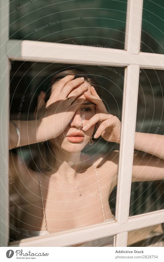 Woman touching face at window pretty Youth (Young adults) Beautiful Considerate Pensive Think Looking away shocked Window Brunette Attractive Human being