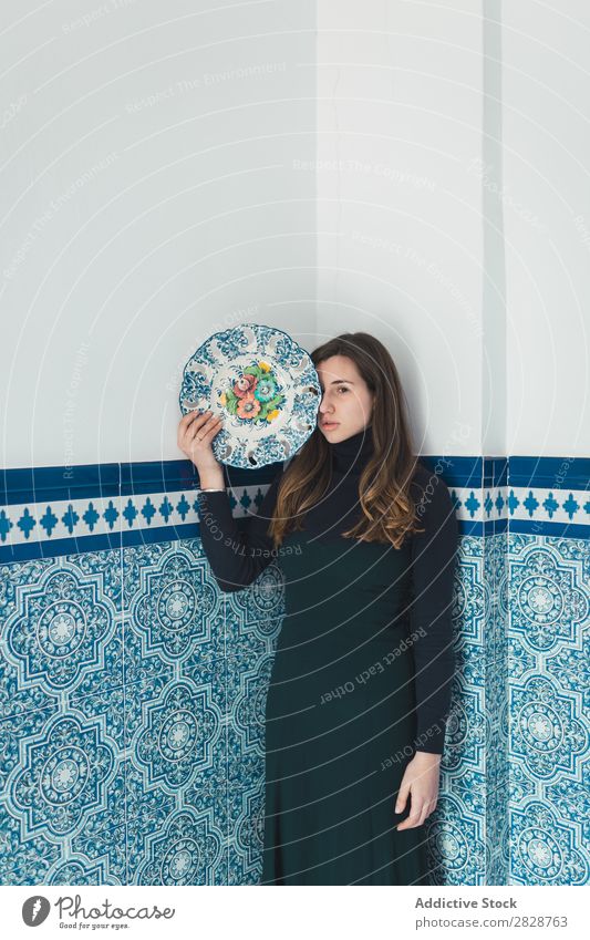Woman standing with colorful plat pretty Youth (Young adults) Beautiful Stand Wall (building) Tile Plate Blue Dish Posture Foyer Brunette Attractive Human being