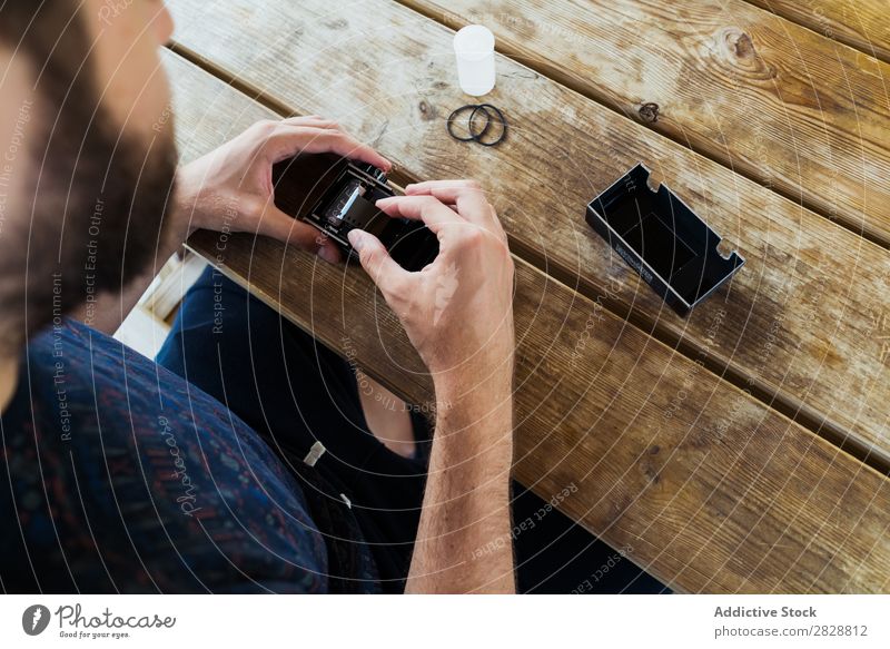 Young man putting new film in camera Man reel photo camera Photographer Nature Creativity Retro Film Camera Vintage Technology Table Sit Relaxation Traveling