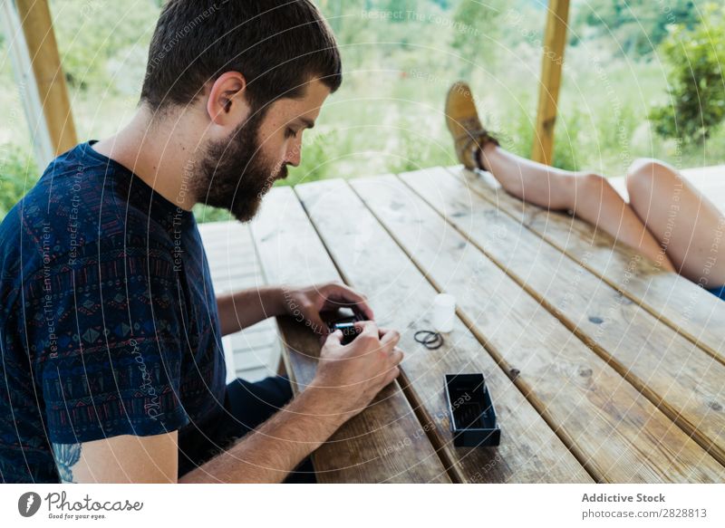 Young man putting new film in camera Man reel photo camera Photographer Nature Creativity Retro Film Camera Vintage Technology Table Sit Relaxation Traveling