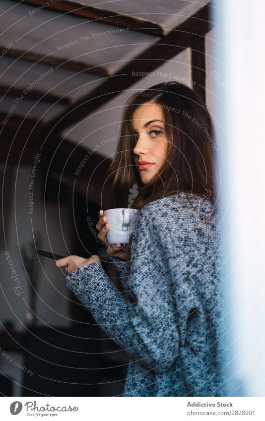 Beautiful model with cup of coffee and smartphone Woman Home Cuddling Coffee Dream human face Posture Cup Pensive Considerate Lifestyle