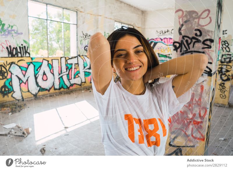 Smiling woman in abandoned room with graffiti Woman Cheerful Posture Looking into the camera Happy Youth (Young adults) grungy Graffiti Multicoloured Room