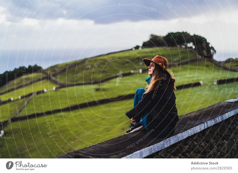 Woman sitting on fence at field Sit Field Green Nature Meadow Fence Relaxation Rest Looking away Hat Spring Summer Grass Landscape Agriculture Rural Sunlight