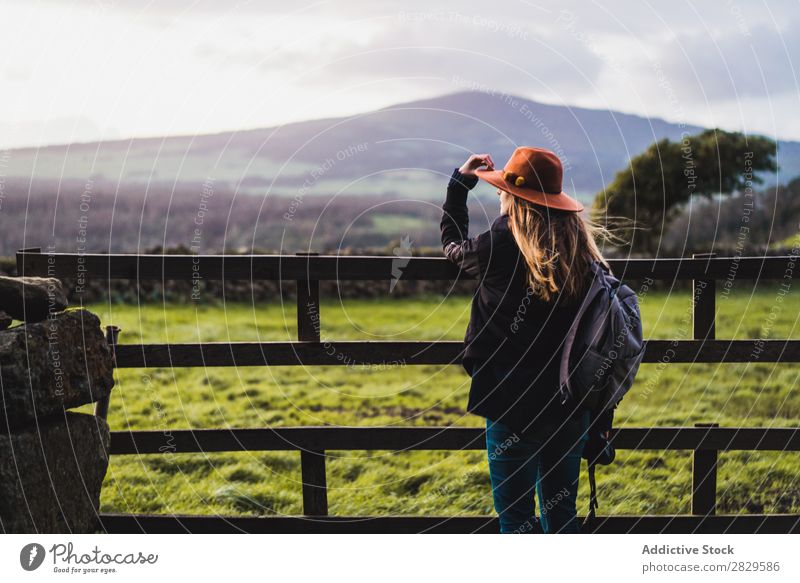 Dreamy woman standing at fence on field Woman Sit Field Green Nature Meadow Fence Stand Relaxation Rest Looking away Hat Spring Summer Grass Landscape