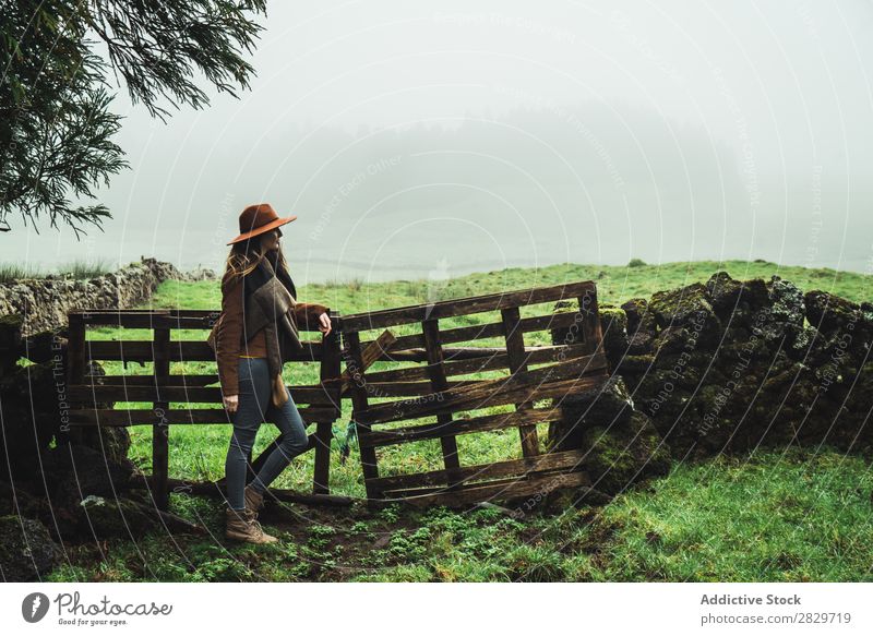 Stylish woman near fence in foggy fields Woman Field Fence Cold Fog Style Dream Green Traveling Vacation & Travel Scene tranquil Destination Agriculture