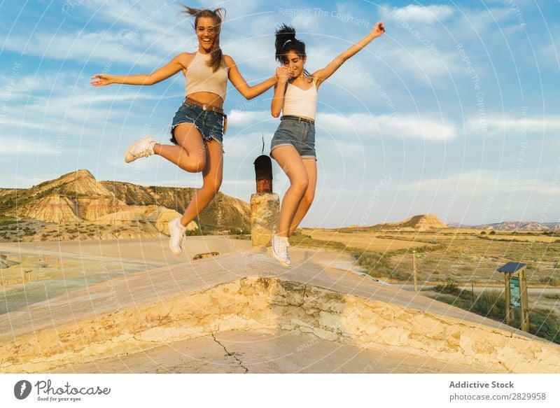 Happy women jumping on hill Woman Cliff Excitement holding hands Freedom Vacation & Travel Success Top Mountain Youth (Young adults) Nature Rock Landscape