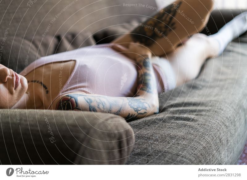 Young pretty woman lying on sofa Human being Tattoo Lie (Untruth) Underwear Sofa Beautiful Body Beauty Photography Youth (Young adults) Adults Woman Crops