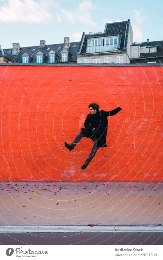 Man jumping at orange wall handsome City Street Jump Wall (building) Orange Joy Trick Youth (Young adults) Town Lifestyle Easygoing Fashion Style Adults Modern