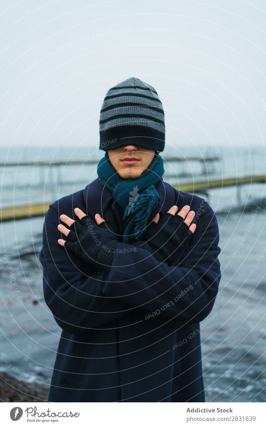 Man putting on hat on eyes Style seaside Cold Coat warm clothes Hat Adjust Ocean Nature Youth (Young adults) Adults Blue Vacation & Travel Water Guy Modern