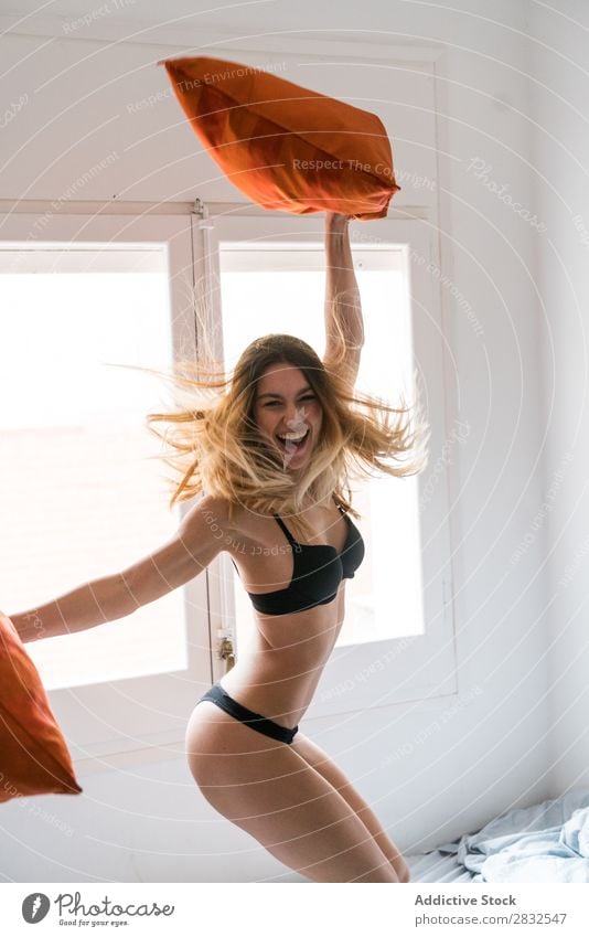 women jumping on giant bed wearing underwear