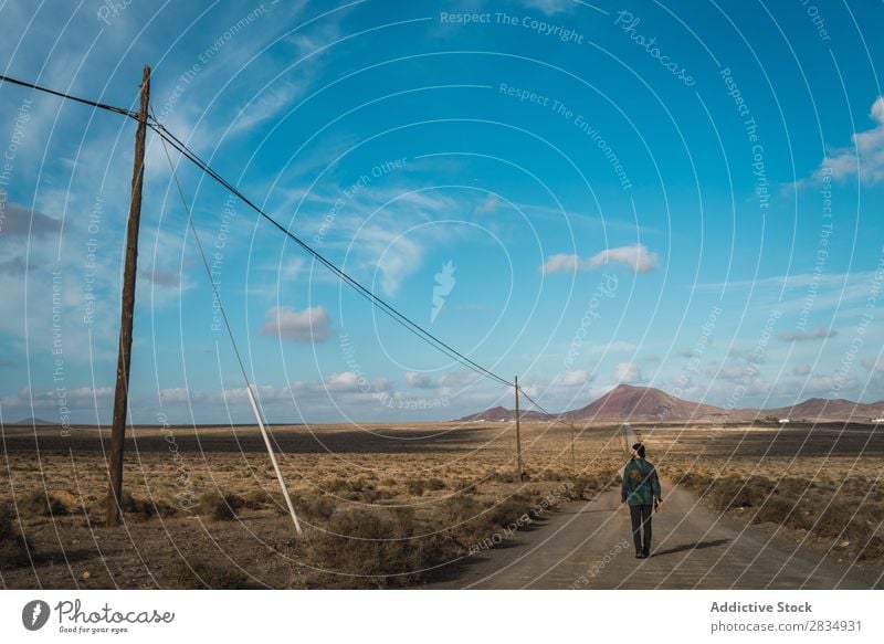 Man walking on road in field Tourist Field Walking Mountain Dry Clouds Nature Landscape Natural Rock Stone Lanzarote Spain Vantage point Vacation & Travel