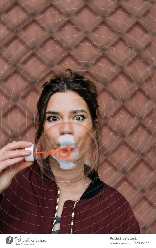 Surprised woman blowing bubbles Bubble Blow Woman surprised Brick Easygoing Wall (building) Happy Human being Hold Caucasian Youth (Young adults) Adults