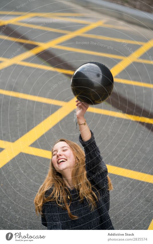 Young girl in Barcelona woman pretty balloon black laughing cheerful mouth opened parking lot lines ground yellow portrait young beautiful hair female sweater