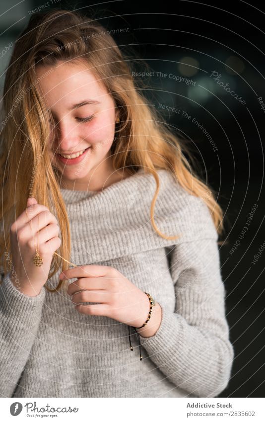 Vertical portrait of young woman touching her necklace. pretty beautiful looking down sensual female dreamy thoughtful collar pensive sweater casual face girl