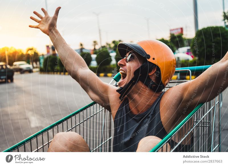 Emotional man in shopping cart Man Shopping Trolley riding Cart pushcart Sunglasses shopper Ride handsome Cheerful Joy Parking lot Human being Markets Humor