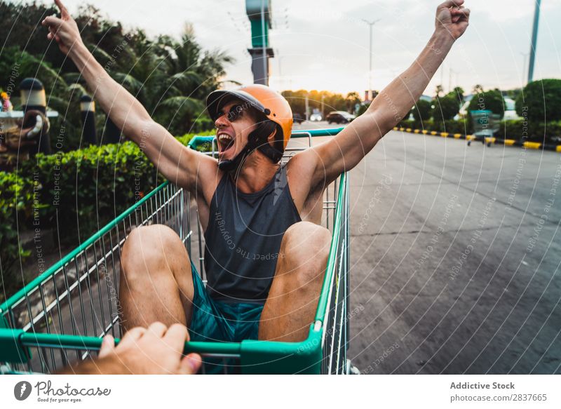 Emotional man in shopping cart Man Shopping Trolley riding Cart pushcart Sunglasses shopper Ride handsome Cheerful Joy Parking lot Human being Markets Humor