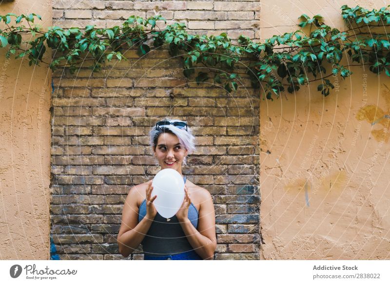 Charming woman posing with balloon Woman Posture Balloon Street Easygoing Summer Emotions Happiness Feminine Brick wall Contentment Expression City Model