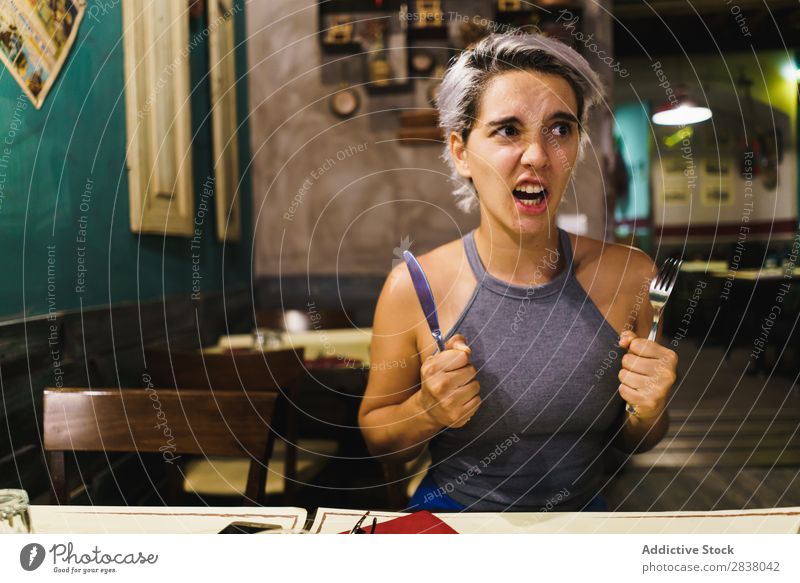 Furious girl posing with silverware Woman Restaurant Appetite having fun Anger Expression facial Emotions humorous hysterical Café Table Adults Stress pretend