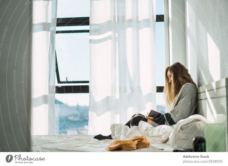 Girl chilling with book in cozy bed Woman Bed Reading Morning Book concentrated Serene Sunlight Peaceful Blonde Safety (feeling of) Home Room Resting To enjoy
