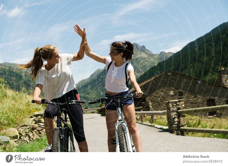 Women on bikes giving high five Woman Athletic Bicycle Smiling Cheerful Team Friendship Sports Cycle Girl Action Lifestyle Cycling Human being workout Mountain