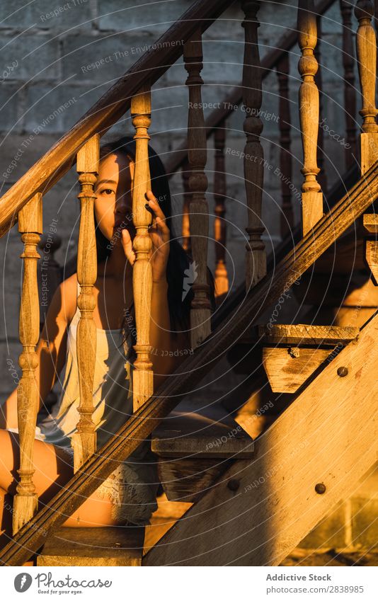 Pensive woman on wooden stairs Woman pretty asian Youth (Young adults) Handrail Wood Steps Evening Sunset Sit Considerate Beautiful Portrait photograph