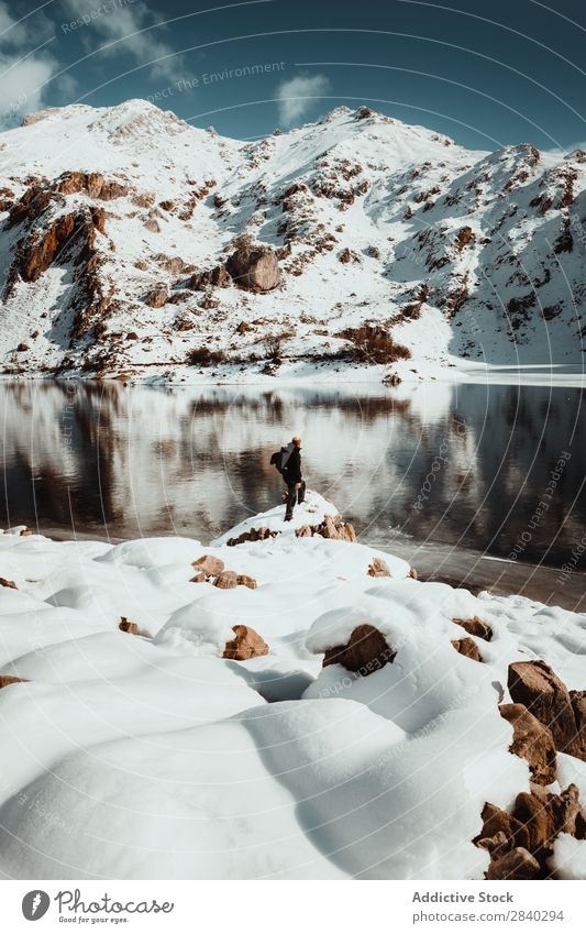 Person on snowy lakeside Human being Lake Mountain traveler Tourism Adventure Snow Reflection Mysterious Rock Landscape Panorama (Format) Nature Wanderlust Sky