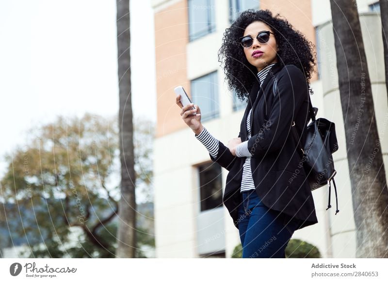 Beautiful woman using her mobile phone in the street. Human being Street Woman Youth (Young adults) Telephone Joy Town texting Internet Cellphone Ethnic
