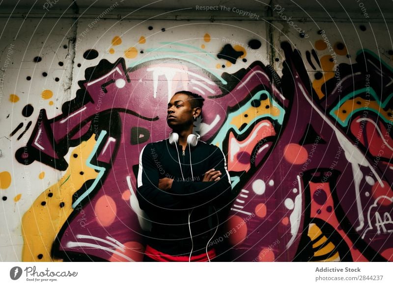 Confident man posing against graffiti Man Posture Uniqueness Graffiti Style Independence Self-confident Black Headphones City Technology hands crossed Easygoing