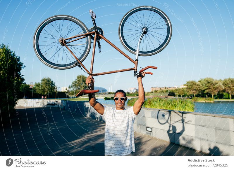 Cheerful man holding bicycle Man Bicycle Hold over head Youth (Young adults) Black Easygoing Stand City Human being Lifestyle Athletic Sports Cycling Posture