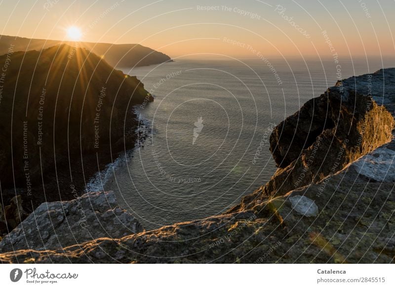 Rising and setting. On the cliff on the beach you can see the sun go down Nature Landscape Elements Cloudless sky Horizon Sun Beautiful weather Rock Waves coast