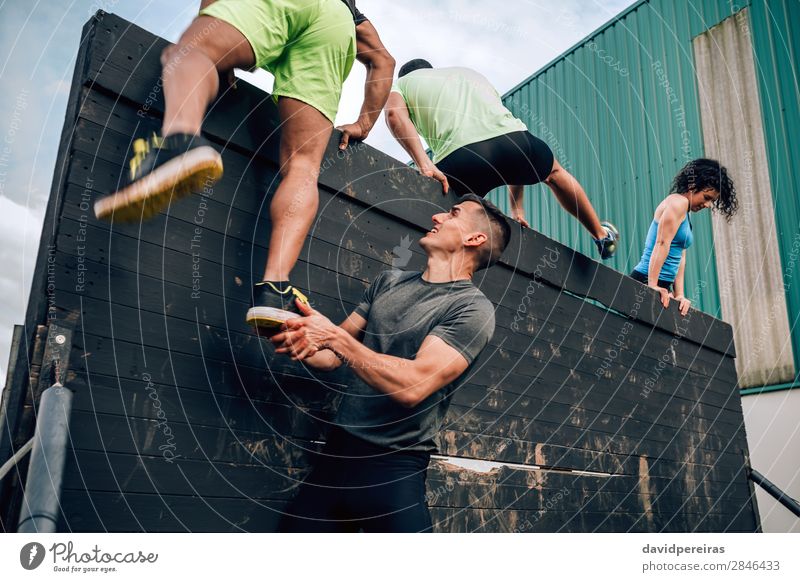 Participants in obstacle course climbing wall Sports Climbing Mountaineering Human being Woman Adults Man Feet Group Authentic Strong Black Effort Competition