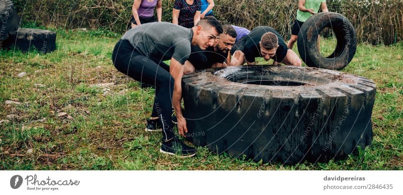 Participants in obstacle course turning truck wheel Sports Internet Human being Woman Adults Man Partner Group Strong Black Power Effort Competition Teamwork