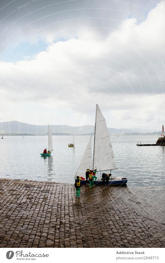 People on shore with sailboat Human being Sailboat Virgin forest Tropical Vacation & Travel Watercraft Transport Set River Preparation amusement Departure