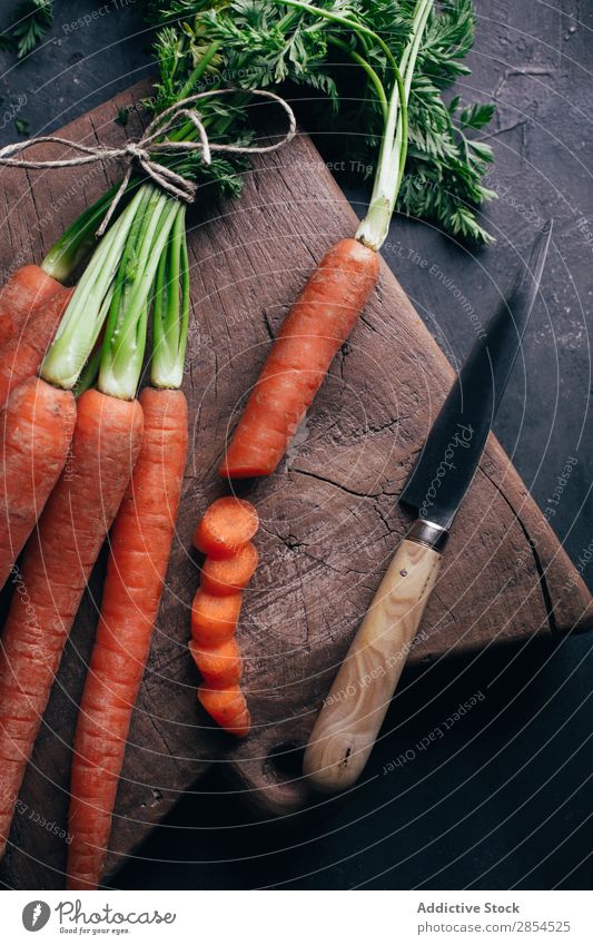 Fresh carrots in a wooden cutting board Background picture bunche Carrot Multicoloured Dark Food Harvest Healthy Knives Metal Nutrition Orange Organic Raw