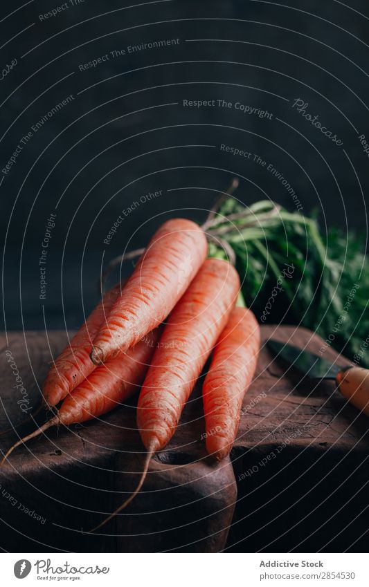 Fresh carrots in a wooden cutting board Background picture bunche Carrot Multicoloured Dark Food Harvest Healthy Knives Metal Nutrition Orange Organic Raw