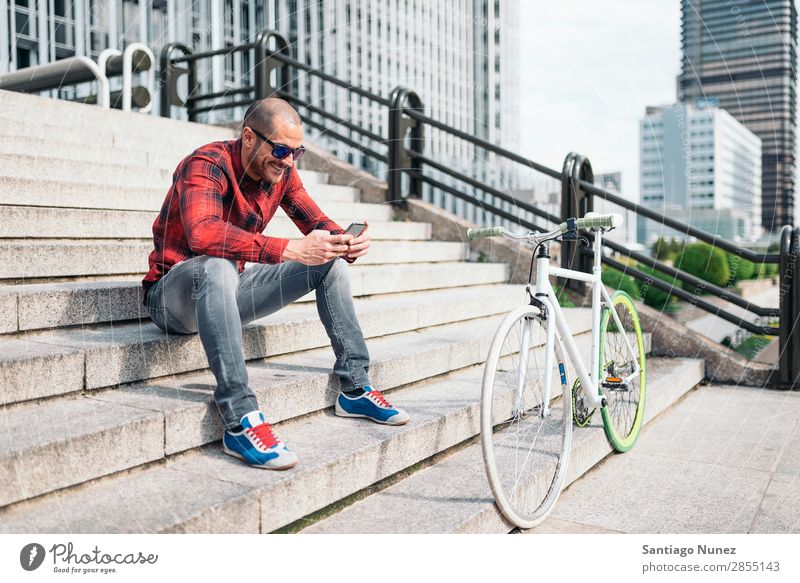 Young man with mobile phone and fixed gear bicycle. Mobile Man Bicycle fixie Telephone Hipster Lifestyle Stand Cycling City Building Solar cell Town Human being