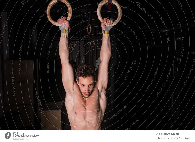 Man hanging on gymnastic rings between darkness in gym Ring Gymnasium Hanging Athletic Youth (Young adults) shirtless obscurity Fitness Guy Equipment workout