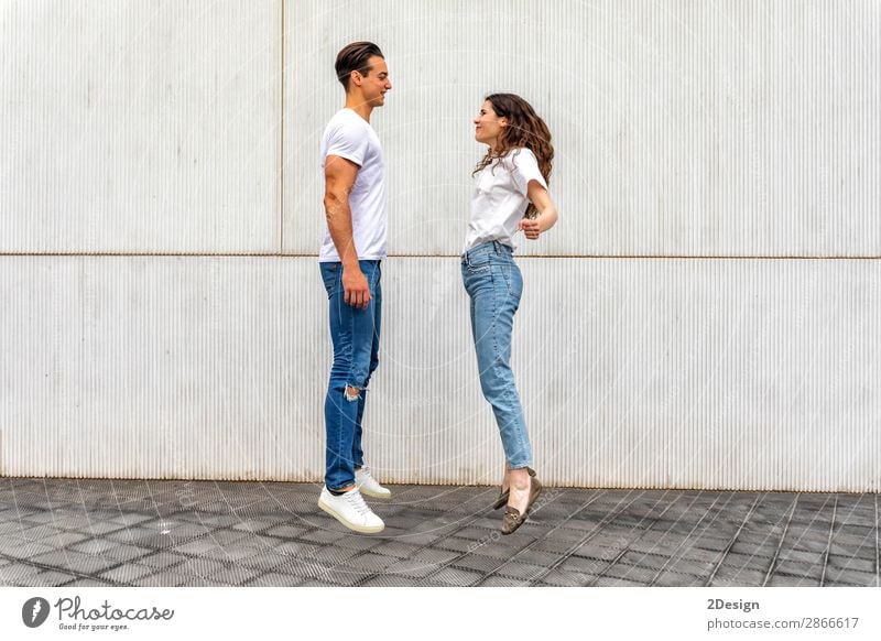 Side view Happy couple in love jumping against grey wall. Lifestyle Joy Leisure and hobbies House (Residential Structure) Human being Masculine Feminine