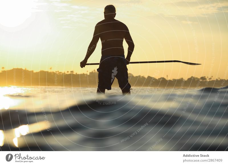 Man with paddle on surf board between waving water at sunset Surfboard Water Surface Sports Bali Indonesia Paddle Silhouette Sunset Sky Ocean Heaven Evening