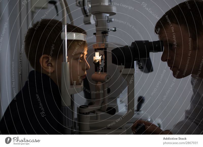 Optician testing a boy's eyes Boy (child) Child clinic device diagnose Display Doctor Examinations and Tests Eyes Person wearing glasses Healthy Hospital