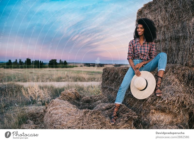 Happy black young woman sitting on a pile of hay Woman Farmer Hay Summer Ethnic Black African Landscape Nature Countries Sky Relaxation Lifestyle