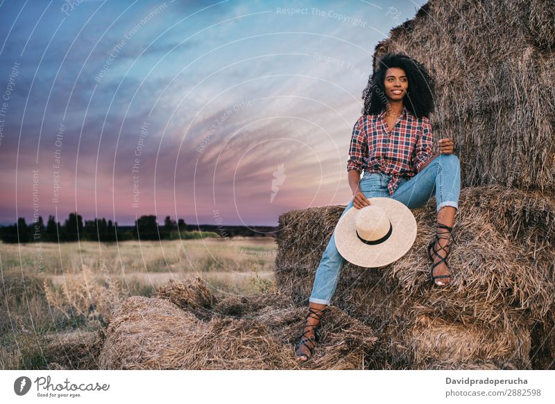 Happy black young woman sitting on a pile of hay Woman Farmer Hay Summer Ethnic Black African Landscape Nature Countries Sky Relaxation Lifestyle