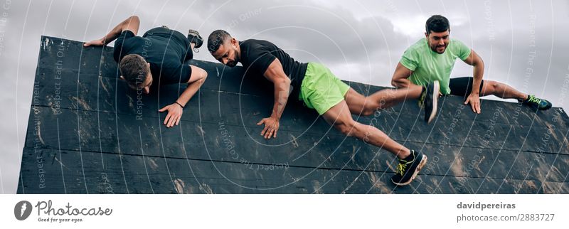 Participants in an obstacle course climbing inverted wall Sports Climbing Mountaineering Internet Human being Man Adults Group Strong Black Effort Energy