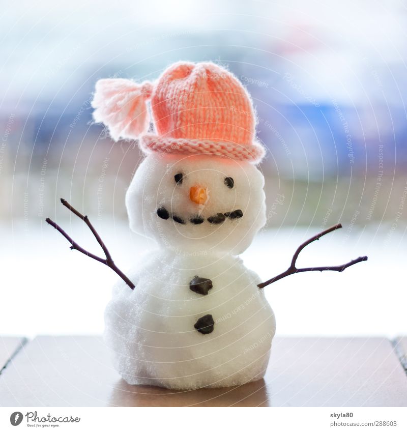 Little cute snowman in a knitted hat and scarf on snow on a sunny