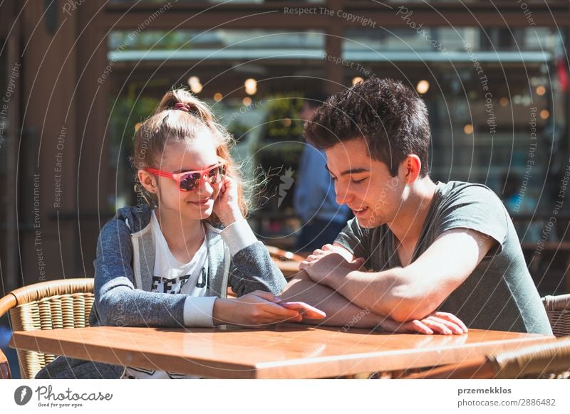 Young people sitting in cafe talking and using mobile phones Lifestyle Joy Happy Summer Table Restaurant Telephone PDA Technology Boy (child) Woman Adults Man