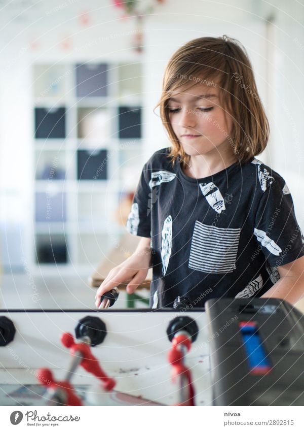 long-haired boy playing at a foosball table Leisure and hobbies Playing Children's game Table soccer Sports Foot ball Masculine Boy (child) 1 Human being